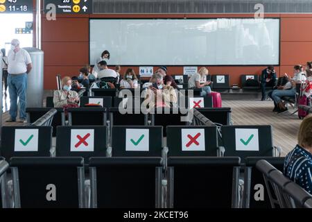 Inside the terminal of Larnaca International Airport Glafcos Clerides LCA during the Covid-19 pandemic. Reduced passenger numbers and flight crew are seen wearing protective equipment like the mandatory facemasks and gloves, keeping distance between them to avoid the spread of the Coronavirus. The world aviation passenger traffic numbers declined due to the travel restrictions, safety measures such as lockdowns, quarantine, PCR and Rapid test before the flights, during the era of the Covid-19. The Coronavirus period hit hard the aviation and travel industry. The island is a popular holiday des Stock Photo