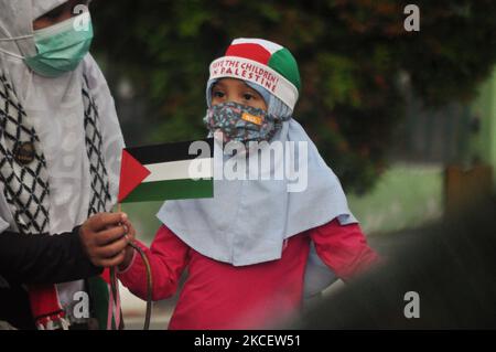 A mother gives a small Palestine flag to her child during a demonstration to defend the rights of the Palestine people from an attack by Israeli soldiers in the city square of Palu, Central Sulawesi Province, on May 18, 2021. (Photo by Faldi Muhammad/NurPhoto) Stock Photo