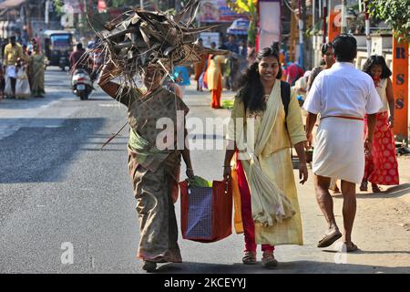 Hindu woman carries a bundle of dried coconut flower sheaths (kothumbu) to be used as fuel for a fire when cooking pongala during the Attukal Pongala Mahotsavam Festival in the city of Thiruvananthapuram (Trivandrum), Kerala, India, on February 19, 2019. The Attukal Pongala Mahotsavam Festival is celebrated by millions Hindu women each year. During this festival women prepare Pongala (rice cooked with jaggery, ghee, coconut and other ingredients) in the open in small pots to as an offering to Goddess Attukal Devi (popularly known as Attukal Amma) who is believed to fulfill the wishes of her de Stock Photo