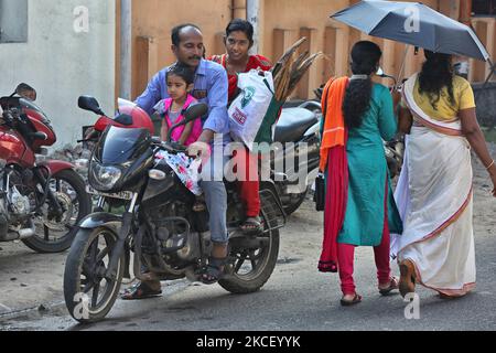 Hindu woman carries a bundle of dried coconut flower sheaths (kothumbu) on a bike to be used as fuel for a fire when cooking pongala during the Attukal Pongala Mahotsavam Festival in the city of Thiruvananthapuram (Trivandrum), Kerala, India, on February 19, 2019. The Attukal Pongala Mahotsavam Festival is celebrated by millions Hindu women each year. During this festival women prepare Pongala (rice cooked with jaggery, ghee, coconut and other ingredients) in the open in small pots to as an offering to Goddess Attukal Devi (popularly known as Attukal Amma) who is believed to fulfill the wishes Stock Photo