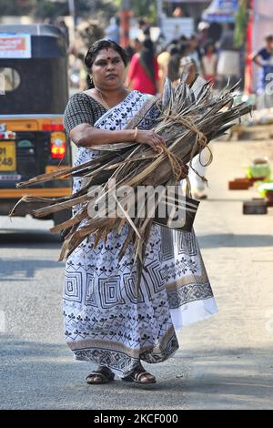 Hindu woman carries a bundle of dried coconut flower sheaths (kothumbu) to be used as fuel for a fire when cooking pongala during the Attukal Pongala Mahotsavam Festival in the city of Thiruvananthapuram (Trivandrum), Kerala, India, on February 19, 2019. The Attukal Pongala Mahotsavam Festival is celebrated by millions Hindu women each year. During this festival women prepare Pongala (rice cooked with jaggery, ghee, coconut and other ingredients) in the open in small pots to as an offering to Goddess Attukal Devi (popularly known as Attukal Amma) who is believed to fulfill the wishes of her de Stock Photo