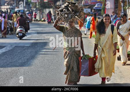 Hindu woman carries a bundle of dried coconut flower sheaths (kothumbu) to be used as fuel for a fire when cooking pongala during the Attukal Pongala Mahotsavam Festival in the city of Thiruvananthapuram (Trivandrum), Kerala, India, on February 19, 2019. The Attukal Pongala Mahotsavam Festival is celebrated by millions Hindu women each year. During this festival women prepare Pongala (rice cooked with jaggery, ghee, coconut and other ingredients) in the open in small pots to as an offering to Goddess Attukal Devi (popularly known as Attukal Amma) who is believed to fulfill the wishes of her de Stock Photo