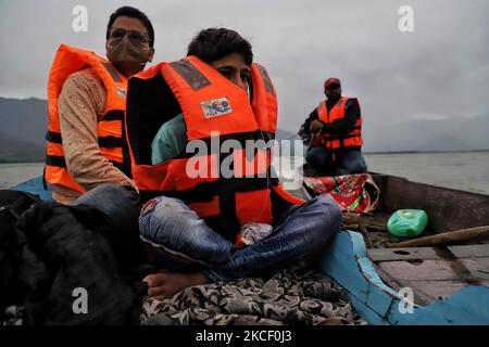 Arslan, 13, Covers himself with a Life Saving Jacket after winds and Rain started in Wular Lake on 20 May 2021. Wular Lake is one of the largest fresh water lakes in Asia. It is the largest freshwater lake in India. It is sited in Bandipora district in Jammu and Kashmir, India. The lake basin was formed as a result of tectonic activity and is fed by the Jhelum River. (Photo by Nasir Kachroo/NurPhoto) Stock Photo