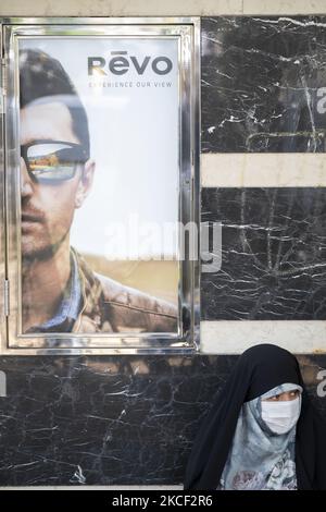 An Iranian veiled woman wearing a protective face mask sits in front of a glasses shop before a gathering at the Palestine square in central Tehran, on May 22, 2021. A group of Iranian men and women have gathered at the Palestine square to celebrate the Victory of the Palestinians over Israel, according to the statement that has been read by a protester. (Photo by Morteza Nikoubazl/NurPhoto) Stock Photo