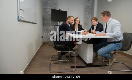 Four colleagues are discussing blueprints in a conference room in an office. Brainstorming of engineers and architects. Stock Photo