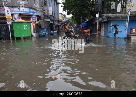 A rickshaw puller waded through a water logged street carrying a passenger in Kolkata, India, on June 17, 2021. Heavy rainfall hampered daily life of the capital city Kolkata. Many places in Kolkata is completely water logged due to heavy rain which started late night of 16th June. (Photo by Sukhomoy Sen/NurPhoto) Stock Photo