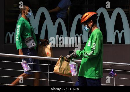 GrabFood delivery riders are seen leaving a McDonald’s restaurant with BTS meal orders on June 21, 2021 in Singapore. McDonald’s Singapore launches the BTS meal today after a three weeks delay due to a resurgent in COVID-19 cases. To prevent long queues amid the COVID-19 pandemic, the BTS meal is only made available on delivery at McDelivery, GrabFood and FoodPanda. The BTS meal, a collaboration between McDonald’s and K-pop supergroup, BTS consists of a box a nine piece Chicken McNuggets, one large-sized fries, one large-sized drink and an exclusive sweet chilli and cajun dipping sauces inspir Stock Photo