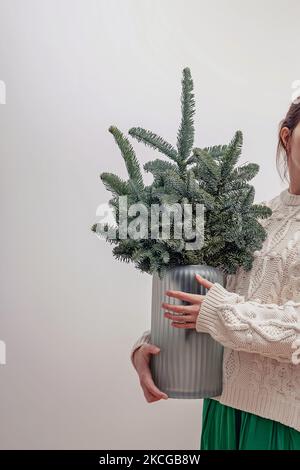 Unrecognizable woman holding a glass vase with decorative Christmas tree branches Stock Photo