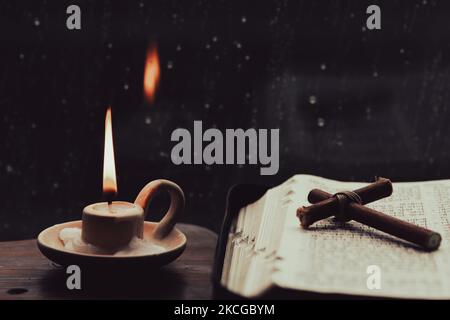 The rain falling on the window, the flowing raindrops, the soothing sound of rain, the cross, the candle, and the Bible symbolizing the suffering, dea Stock Photo