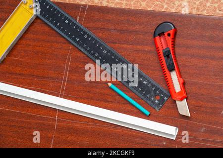 Construction or stationery knife, pencil and ruler on the board. View of the tools Stock Photo