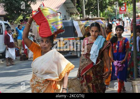 Hindu women carrying items to be used to cook pongala during the Attukal Pongala Mahotsavam Festival in the city of Thiruvananthapuram (Trivandrum), Kerala, India, on February 19, 2019. The Attukal Pongala Mahotsavam Festival is celebrated by millions Hindu women each year. During this festival women prepare Pongala (rice cooked with jaggery, ghee, coconut as well as other ingredients) in the open in small pots to please the Goddess Attukal Devi (popularly known as Attukal Amma). Pongala (which literally means to boil over) is a ritualistic offering of a sweet dish, consisting of rice porridge Stock Photo