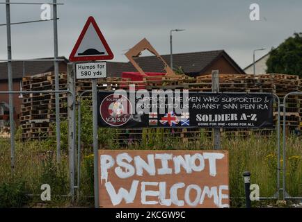 Stacked wooden pallets to build the Eleventh Night bonfire, ahead of the Twelfth of July celebrations, and 'PSNI Not Welcome' inscription attached to the fence, seen on Shankill Road in Belfast. On Saturday, 03 July 2021, in Belfast, Northern Ireland (Photo by Artur Widak/NurPhoto) Stock Photo