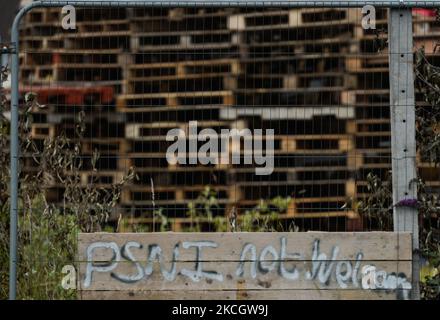 Stacked wooden pallets to build the Eleventh Night bonfire, ahead of the Twelfth of July celebrations, and 'PSNI Not Welcome' inscription attached to the fence, seen on Shankill Road in Belfast. On Saturday, 03 July 2021, in Belfast, Northern Ireland (Photo by Artur Widak/NurPhoto) Stock Photo