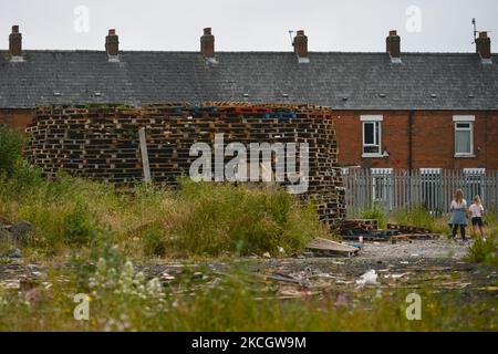 Stacked wooden pallets to build the Eleventh Night bonfire, ahead of the Twelfth of July celebrations, and 'PSNI Not Welcome' inscription attached to the fence, seen on Shankill Road in Belfast. On Saturday, 03 July 2021, in Belfast, Northern Ireland (Photo by Artur Widak/NurPhoto) Stock Photo