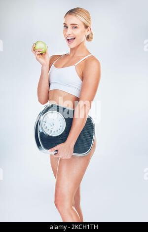 Apple, fitness and woman with a scale for fat loss with a healthy diet after a workout, exercise and training. Weightloss, portrait and happy girl Stock Photo