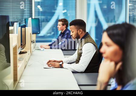 Hes a busy worker. a group of designers working on computers in an office. Stock Photo