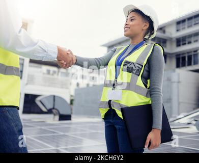 Engineering team handshake, black woman at solar panel construction site or architecture project partnership. Working on building roof, industrial Stock Photo