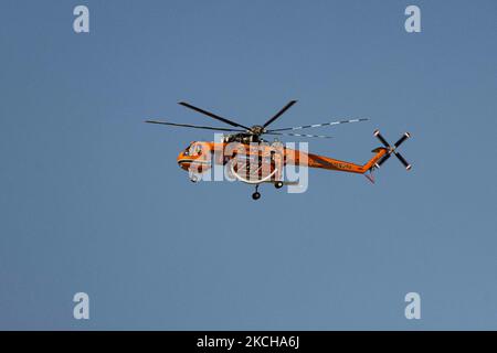 A Sikorsky S-64E Skycrane, registered N173AC and operated by Erickson Inc. - Erickson Air Crane, firefighting helicopter drops water over the fire on the hills with bushes and illegally dump garbage place near the industrial area of Thessaloniki and the residential area near settlement of Diavata and the village of Neochorodouda in Oreokastro and Delta Municipality assisting the ground force to extinguish the bushfire. Greece is having many fires, wild fires, forest firest etc as the country is facing a continuous heatwave and arid season with a month almost with no rain and high temperatures, Stock Photo