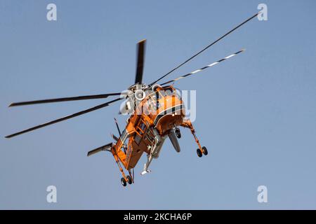 A Sikorsky S-64E Skycrane, registered N173AC and operated by Erickson Inc. - Erickson Air Crane, firefighting helicopter drops water over the fire on the hills with bushes and illegally dump garbage place near the industrial area of Thessaloniki and the residential area near settlement of Diavata and the village of Neochorodouda in Oreokastro and Delta Municipality assisting the ground force to extinguish the bushfire. Greece is having many fires, wild fires, forest firest etc as the country is facing a continuous heatwave and arid season with a month almost with no rain and high temperatures, Stock Photo