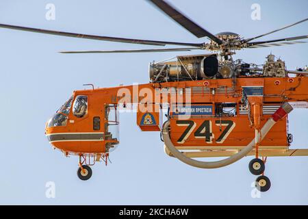 A Sikorsky S-64E Skycrane, registered N173AC and operated by Erickson Inc. - Erickson Air Crane, firefighting helicopter drops water over the fire on the hills with bushes and illegally dump garbage place near the industrial area of Thessaloniki and the residential area near settlement of Diavata and the village of Neochorodouda in Oreokastro and Delta Municipality assisting the ground force to extinguish the bushfire. Greece is having many fires, wild fires, forest firest etc as the country is facing a continuous heatwave and arid season with a month almost with no rain and high temperatures, Stock Photo