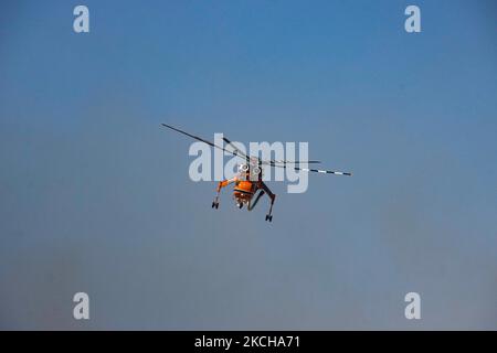 A Sikorsky S-64E Skycrane, registered N173AC and operated by Erickson Inc. - Erickson Air Crane, firefighting helicopter drops water over the fire on the hills with bushes and illegally dump garbage place near the industrial area of Thessaloniki and the residential area near settlement of Diavata and the village of Neochorodouda in Oreokastro and Delta Municipality assisting the ground force to extinguish the bushfire. Greece is having many fires, wild fires, forest firest etc as the country is facing a continuous heatwave and arid season with a month almost with no rain and high temperatures, Stock Photo