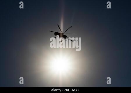 Silhouette of a fire fighting helicopter passing infront of the sun. A Sikorsky S-64E Skycrane, registered N173AC and operated by Erickson Inc. - Erickson Air Crane, firefighting helicopter drops water over the fire on the hills with bushes and illegally dump garbage place near the industrial area of Thessaloniki and the residential area near settlement of Diavata and the village of Neochorodouda in Oreokastro and Delta Municipality assisting the ground force to extinguish the bushfire. Greece is having many fires, wild fires, forest firest etc as the country is facing a continuous heatwave an Stock Photo