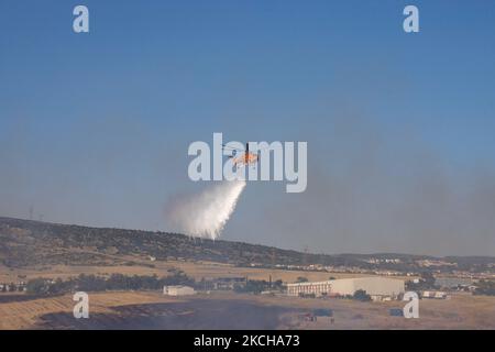 A Sikorsky S-64E Skycrane, registered N173AC and operated by Erickson Inc. - Erickson Air Crane, firefighting helicopter drops water over the fire on the hills with bushes and illegally dump garbage place near the industrial area of Thessaloniki and the residential area near settlement of Diavata and the village of Neochorodouda in Oreokastro and Delta Municipality assisting the ground force to extinguish the bushfire. Greece is having many fires, wild fires, forest firest etc as the country is facing a continuous heatwave and arid season with a month almost with no rain and high temperatures, Stock Photo