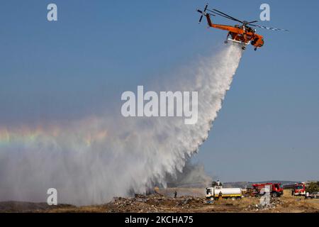 A Sikorsky S-64E Skycrane, registered N173AC and operated by Erickson Inc. - Erickson Air Crane, firefighting helicopter drops water over the fire on the hills with bushes and illegally dump garbage place near the industrial area of Thessaloniki and the residential area near settlement of Diavata and the village of Neochorodouda in Oreokastro and Delta Municipality assisting the ground force to extinguish the bushfire. Greece is having many fires, wild fires, forest firest etc as the country is facing a continuous heatwave and arid season with a month almost with no rain and high temperatures, Stock Photo