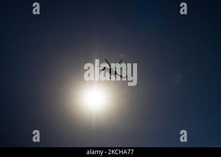 Silhouette of a fire fighting helicopter passing infront of the sun. A Sikorsky S-64E Skycrane, registered N173AC and operated by Erickson Inc. - Erickson Air Crane, firefighting helicopter drops water over the fire on the hills with bushes and illegally dump garbage place near the industrial area of Thessaloniki and the residential area near settlement of Diavata and the village of Neochorodouda in Oreokastro and Delta Municipality assisting the ground force to extinguish the bushfire. Greece is having many fires, wild fires, forest firest etc as the country is facing a continuous heatwave an Stock Photo