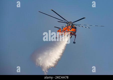 A Sikorsky S-64E Skycrane, registered N173AC and operated by Erickson Inc. - Erickson Air Crane, firefighting helicopter drops water over the fire on the hills with bushes and illegally dump garbage place near the industrial area of Thessaloniki and the residential area near settlement of Diavata and the village of Neochorodouda in Oreokastro and Delta Municipality assisting the ground force to extinguish the bushfire. Greece is having many fires, wild fires, forest firest etc as the country is facing a continuous heatwave and arid season with a month almost with no rain and high temperatures, Stock Photo