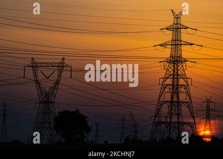 Summer sunset in Greece with electrical pylons near Thessaloniki city. High voltage electricity poles - towers during the sunset time in the magic hour. The metal towers as seen in the sunset in the Greek countryside, distribute electric energy from the power station where electricity is generated in coal production, across the country. The electric wires, the grid and pillars or power pylons are seen as silhouettes in the colorful cloudy dusk evening sky. Oreokastro, Thessaloniki in Greece on July 25, 2021 (Photo by Nicolas Economou/NurPhoto) Stock Photo
