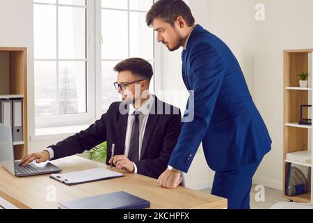 Male colleagues at work in office talking while working together on joint business project. Stock Photo