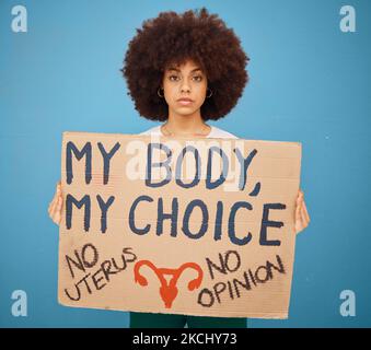 Protest, human rights and woman with a poster for abortion, body freedom and justice against a blue studio background. Choice, equality and portrait Stock Photo
