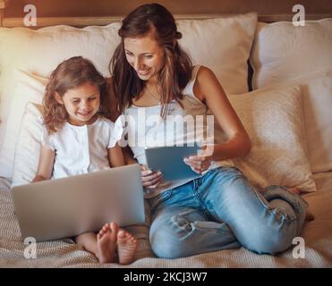 Theyre never bored when theyre online. a little girl using a laptop and her mother using a digital tablet at home. Stock Photo