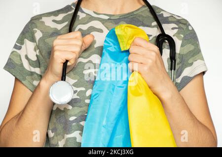 Military nurse with a stethoscope and the flag of Ukraine in her hands on an isolated background, a military doctor in Ukraine Stock Photo