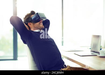 Business and relaxation done in one. a businessman wearing a VR headset while leaning back in his office chair at work. Stock Photo