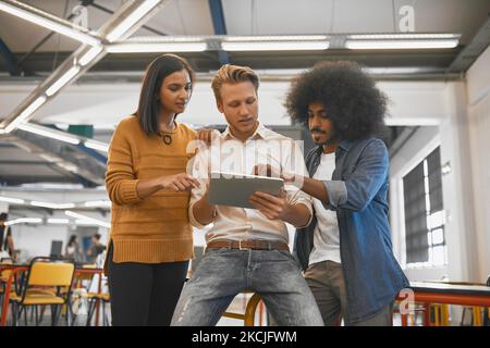 Getting some much needed input. three young businesspeople looking at a tablet in their office. Stock Photo
