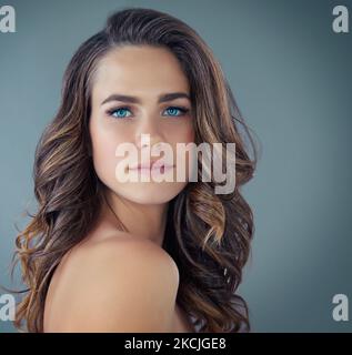 Shes a blue-eyed beauty. Cropped portrait of a beautiful young woman posing against a grey background in the studio. Stock Photo