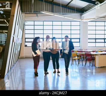Sharing their thoughts, opinions and ideas. a group of designers having a discussion while walking through a office. Stock Photo
