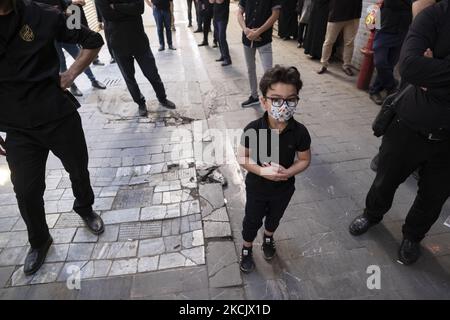 An Iranian young boy wearing a protective face mask beats himself in a holy ceremony to commemorate Tasoua, a day ahead of Ashura, at the Grand Bazaar in southern Tehran amid the COVID-19 delta variant outbreak in Iran, August 18, 2021. (Photo by Morteza Nikoubazl/NurPhoto) Stock Photo