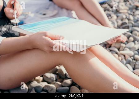 Unrecognizable woman's hands holding her own sea beach scenery watercolor painting. Amateur painter. Creative female artist drawing the picture at the Stock Photo