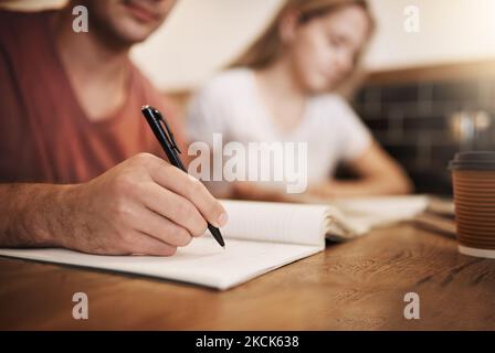 Making extensive study notes. two unrecognizable students having a study session at a table in a cafe. Stock Photo