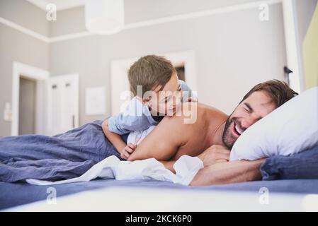 Its late already...a handsome young man being woken up by his son. Stock Photo