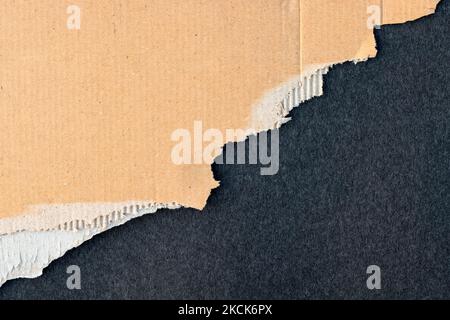Brown scrap paper of cardboard with torn edge on textured dark background Stock Photo