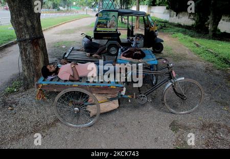 Homeless trolley rickshaw puller rests in the shadow of the wayside tree as they takes break from their works near to the daily market area in between the lockdown relaxation period in the eastern Indian state Odisha's capital city Bhubaneswar. (Photo by STR/NurPhoto) Stock Photo