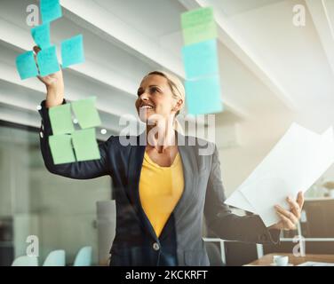 Shes a cunning strategist. a mature corporate businesswoman planning on a glass wipe board. Stock Photo