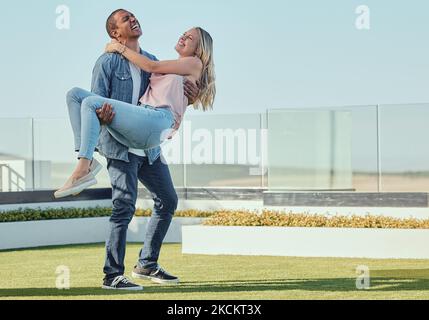Love, carrying and fun with a couple laughing or joking together outdoor in summer for bonding. Dating, happy and romance with an affectionate young Stock Photo