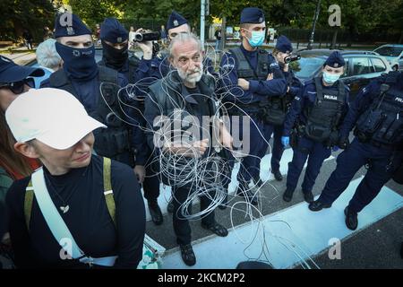 A protester wrapped in metal wire symbolizing the newly built concertina wire fence along the Belarusian border is seen in Warsaw, Poland on 6 September, 2021. Several hundred protesters gathered in front of the Sejm, the Polish parliament to protest a presidential decree which invoked a state of emergency along the border region with Belarus. While proponents argue that Poland is under threat of a hybrid war by Belarus which is pushing migrants from the Middle East over the border opponents argue the law is a political tool resulting in further abuse of vulnerable people. Poland has been accu Stock Photo