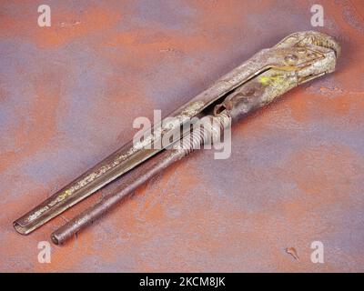 Old rusty adjustable spanner on a grunge orange background Stock Photo
