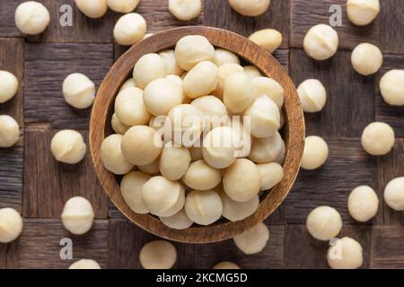 macadamia nuts peeledin bowl on wooden table background. Stock Photo